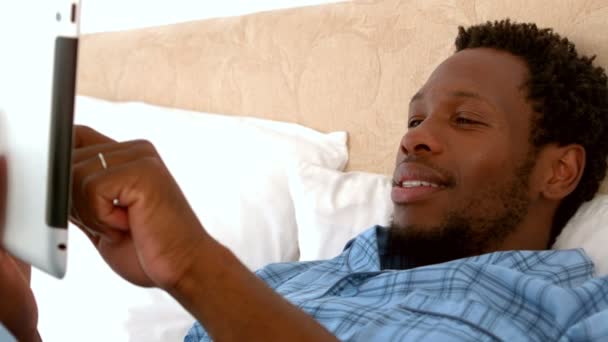 Человек расслабляется в постели с помощью планшета ПК — стоковое видео