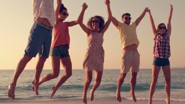 Amigos saltando juntos en la playa — Vídeo de stock