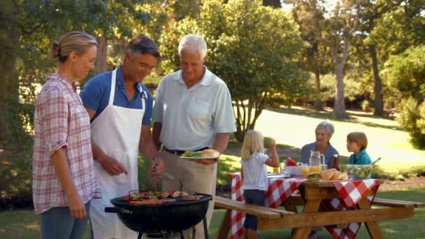Man doet barbecue voor zijn familie — Stockvideo