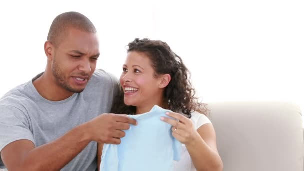 Couple sur le canapé tenant un vêtement de bébé — Video