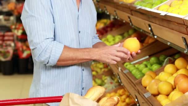 Un homme cueillant des fruits dans un supermarché — Video