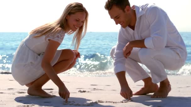 Feliz pareja dibujando corazón en la arena — Vídeos de Stock