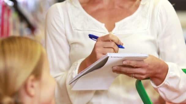 Sonriente madre revisando la lista de comestibles — Vídeos de Stock