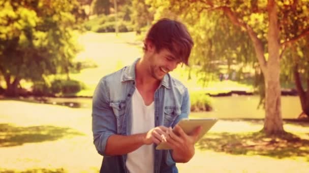 Man using tablet and laughing in the park — Stock Video