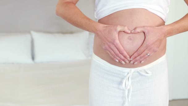 Mujer embarazada haciendo forma de corazón en el bulto — Vídeos de Stock