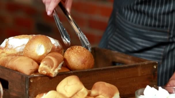 Lächelnder Kellner, der mit einer Zange Brötchen aufräumt — Stockvideo