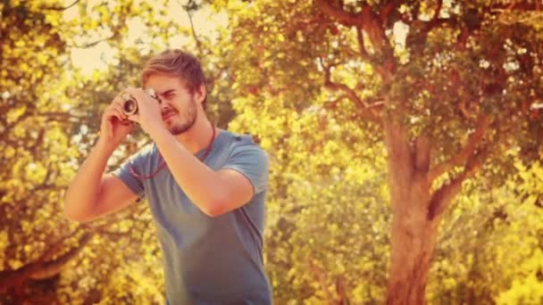 Hombre usando cámara fotográfica retro en el parque — Vídeos de Stock