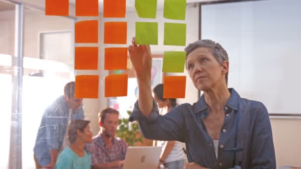 Businesswoman looking at post it with her colleagues — Stock Video