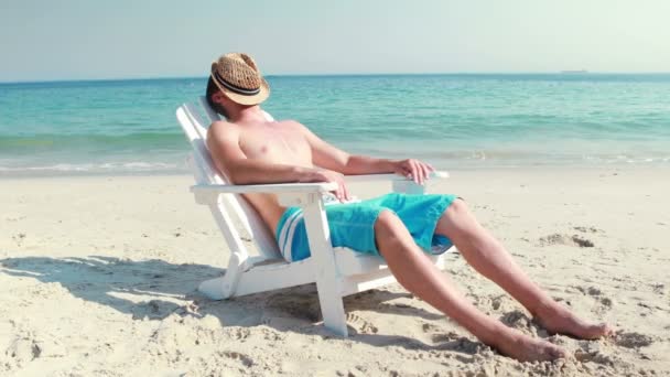 Man koppla av på en solstol på stranden — Stockvideo