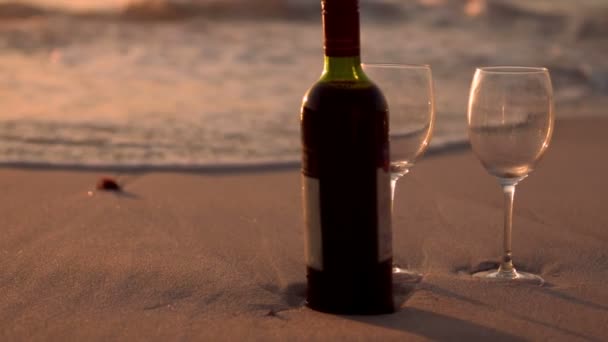 Fles wijn en bril op het strand zand — Stockvideo