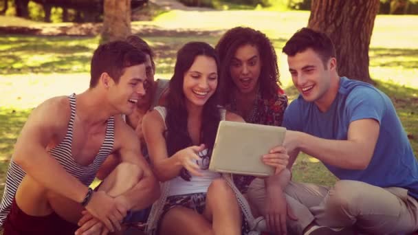 Przyjaciele przy pomocy tabletu w parku — Wideo stockowe