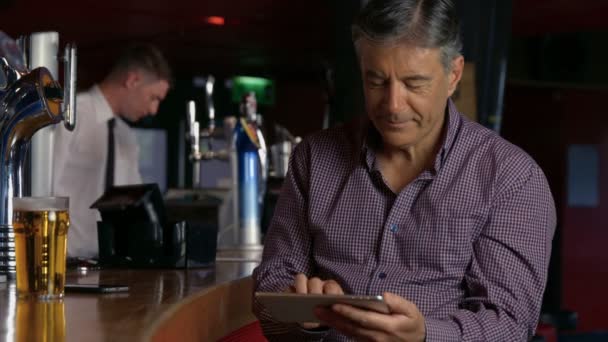 Man har en pint i baren med hjälp av Tablet PC — Stockvideo