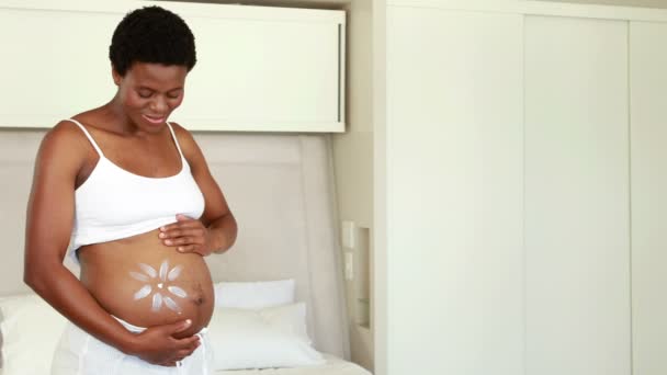 Беременная женщина намазывает кремом живот — стоковое видео