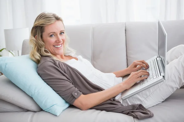 Mujer acostada en el sofá utilizando el ordenador portátil — Foto de Stock
