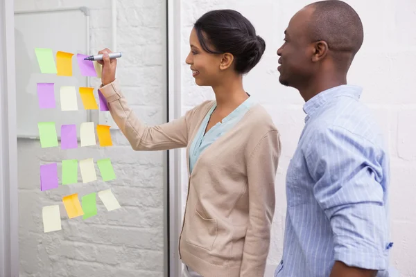 Businesswoman writing on sticky notes — Stock Photo, Image