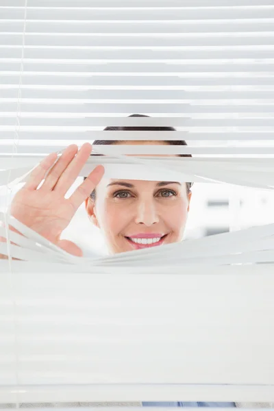 Zakenvrouw door blinden uitkijken — Stockfoto