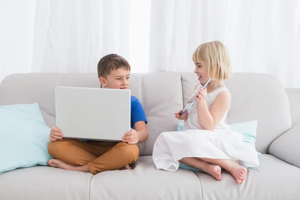 Siblings using laptop and tablet — Stock Photo, Image