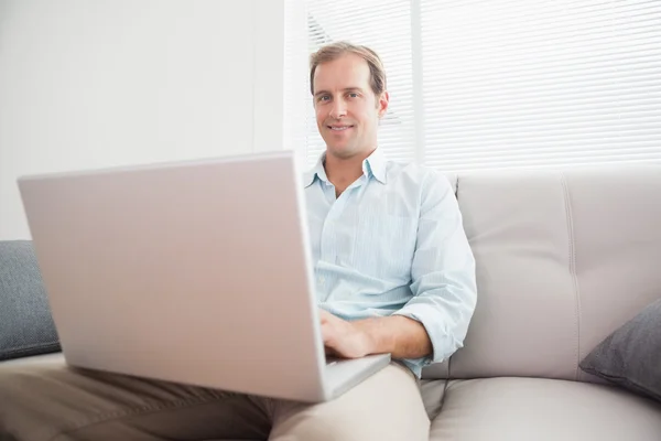 Mann benutzt Laptop auf Couch — Stockfoto