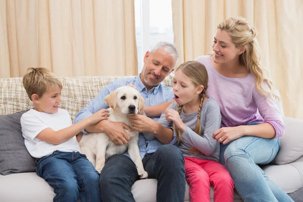 Föräldrar och barn som leker med valp — Stockfoto