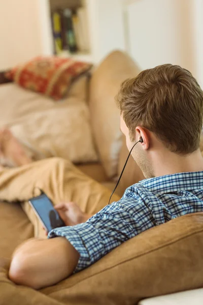 Homem ouvindo música no sofá — Fotografia de Stock