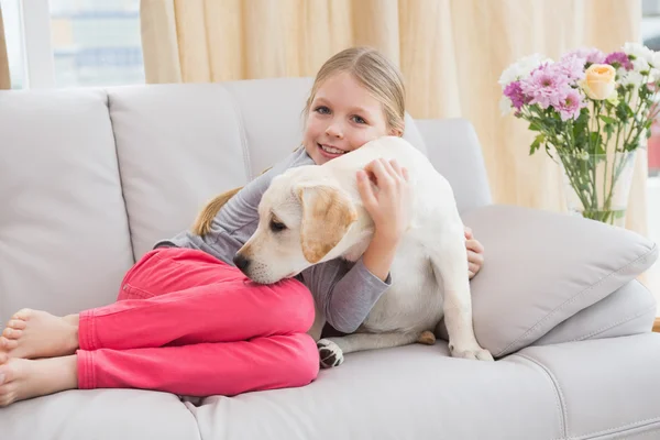 Fille avec chiot sur canapé — Photo