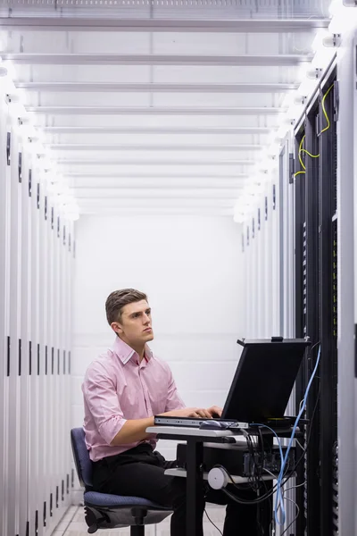 Technicus gebruik laptop voor het onderzoeken van servers — Stockfoto