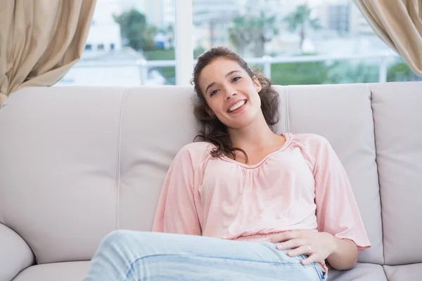 Mujer sonriendo a la cámara en el sofá —  Fotos de Stock