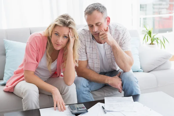Couple calculating bills on couch — Stock Photo, Image