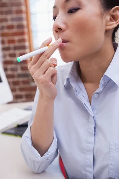 Businesswoman smoking electronic cigarette — Stock Photo, Image