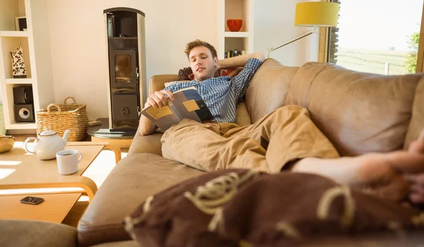 Muž čtení na gauči — Stock fotografie