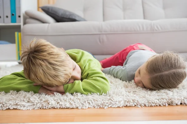 Broers en zussen liggen op tapijt — Stockfoto