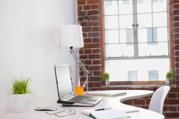 Laptop on desk with glasses and notepad — Stock Photo, Image