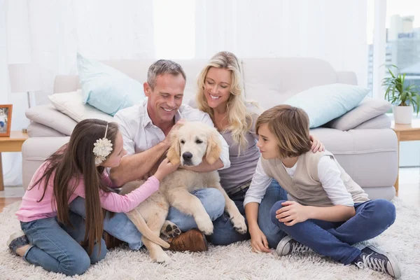 Familie mit gelbem Labrador auf Teppich — Stockfoto