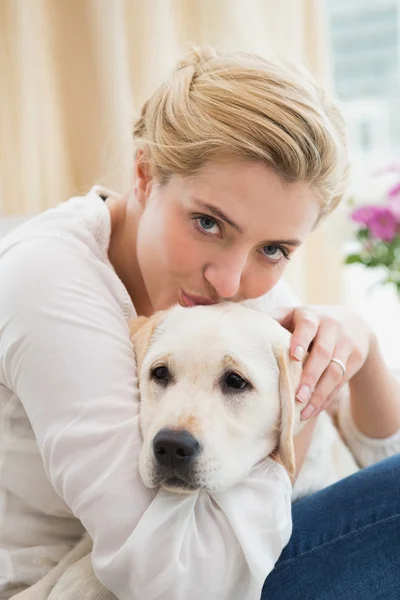 Woman cuddling with puppy on sofa — Stock Photo, Image