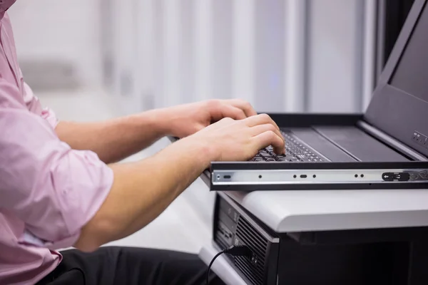 Technicus gebruik laptop voor het onderzoeken van servers — Stockfoto