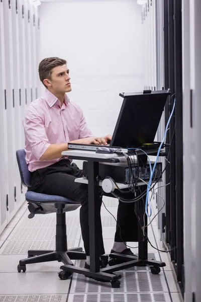 Technicus gebruik laptop voor het onderzoeken van servers — Stockfoto