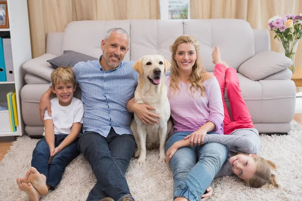 Genitori e figli sul tappeto con labrador — Foto Stock