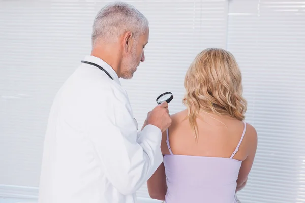 Médico examinando paciente com lupa — Fotografia de Stock