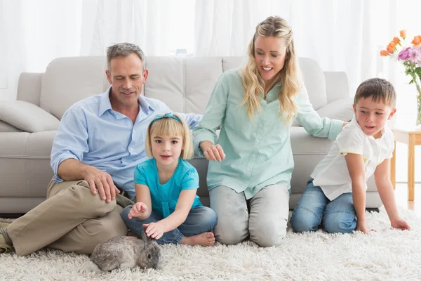 Familie met konijn op tapijt — Stockfoto