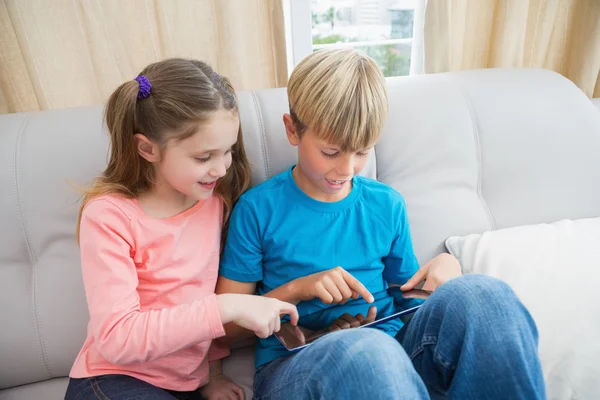 Hermanos usando la tableta PC en el sofá — Foto de Stock