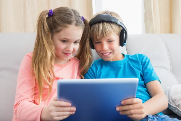 Hermanos usando la tableta PC en el sofá —  Fotos de Stock