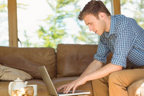 Mann benutzt Laptop auf Couch — Stockfoto