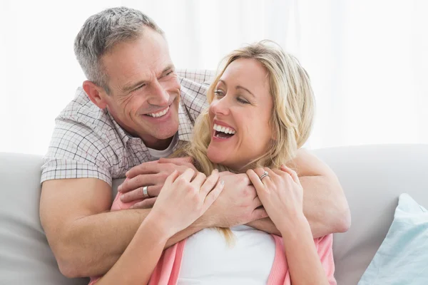 Man hugging wife on couch — Stock Photo, Image