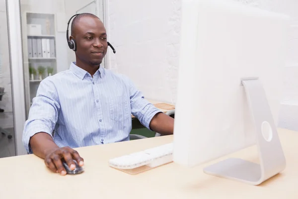 Businessman wearing headset while using computer — Stock Photo, Image