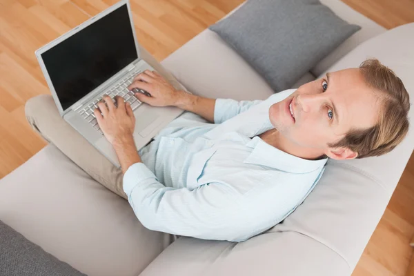 Hombre usando el ordenador portátil en el sofá Fotos De Stock Sin Royalties Gratis