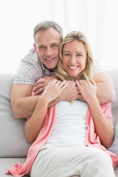 Man hugging wife on couch — Stock Photo, Image