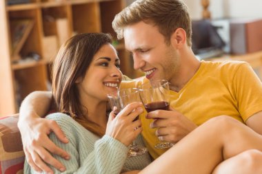 couple cuddling on couch with red wine clipart