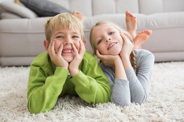 Silblings sonriendo a la cámara en la alfombra — Foto de Stock