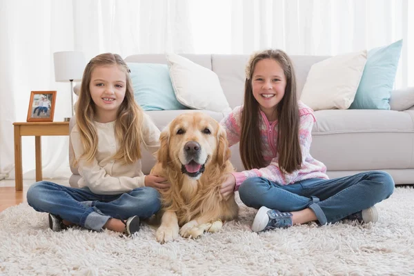 Siostry pieszczoty złoty pies myśliwski na dywan — Zdjęcie stockowe