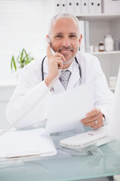 Doutor telefonando e usando o computador — Fotografia de Stock